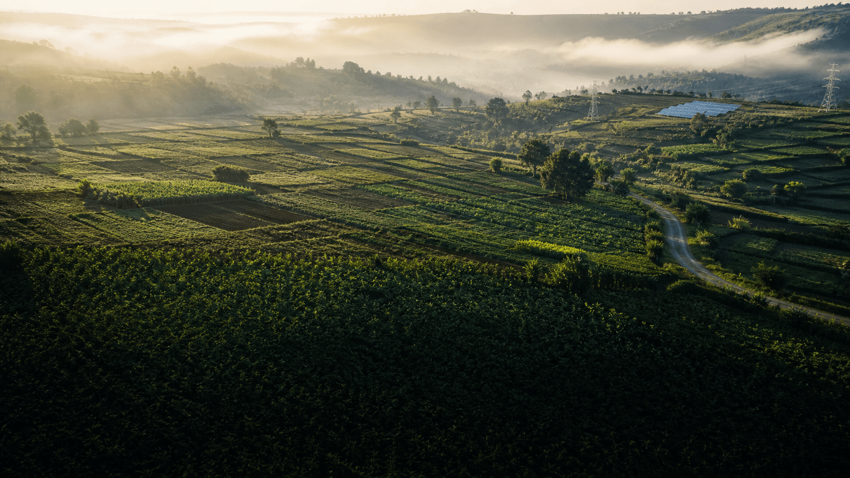 Aerial view of cultivated Kenyan highland fields with clean-energy infrastructure at sunrise